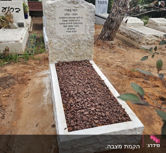 מצבה עם כיתוב בעברית ואבנים חומות